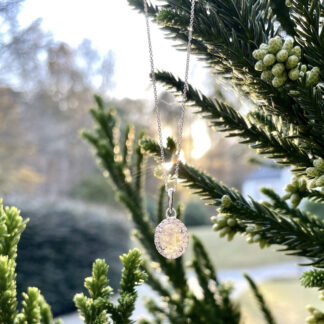 White salt and pepper necklace outside hanging on a tree.